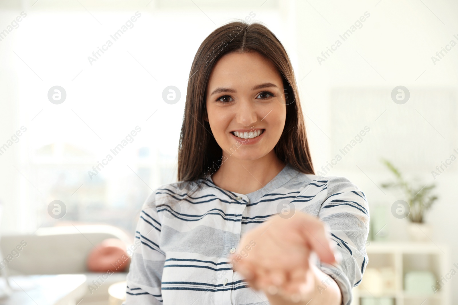 Photo of Young woman looking at camera and using video chat in home office