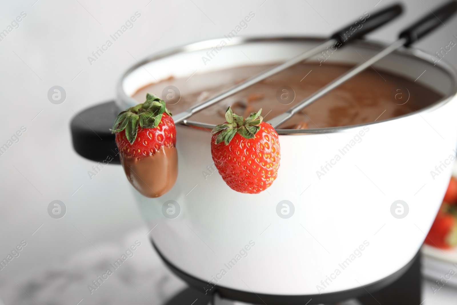 Photo of Pot with chocolate fondue and ripe strawberries on table, closeup