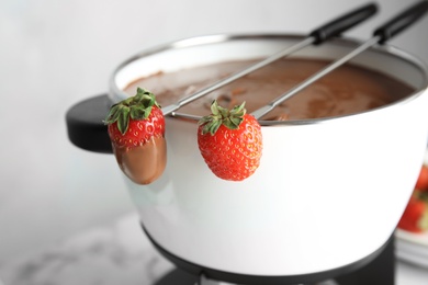 Photo of Pot with chocolate fondue and ripe strawberries on table, closeup