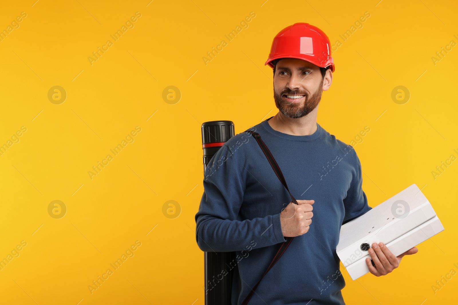 Photo of Architect in hard hat with drawing tube and folders on orange background, space for text