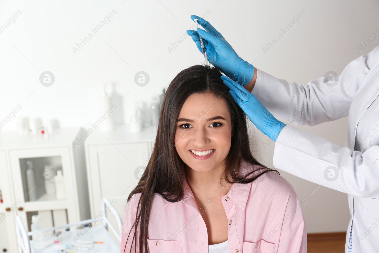 Photo of Young woman with hair loss problem receiving injection in salon