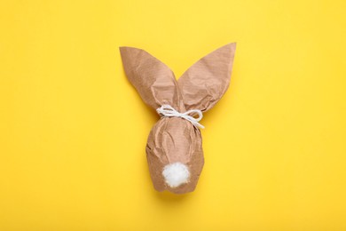 Easter bunny made of craft paper and egg on yellow background, top view