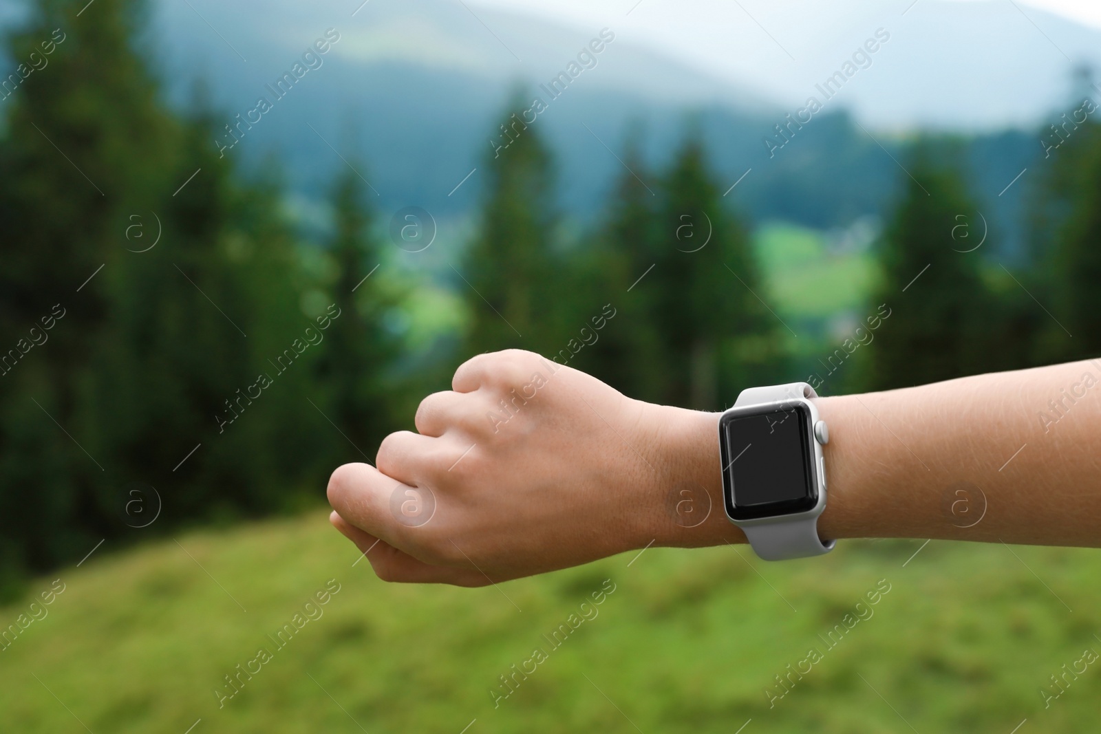 Photo of Woman checking smart watch with blank screen in wilderness, closeup