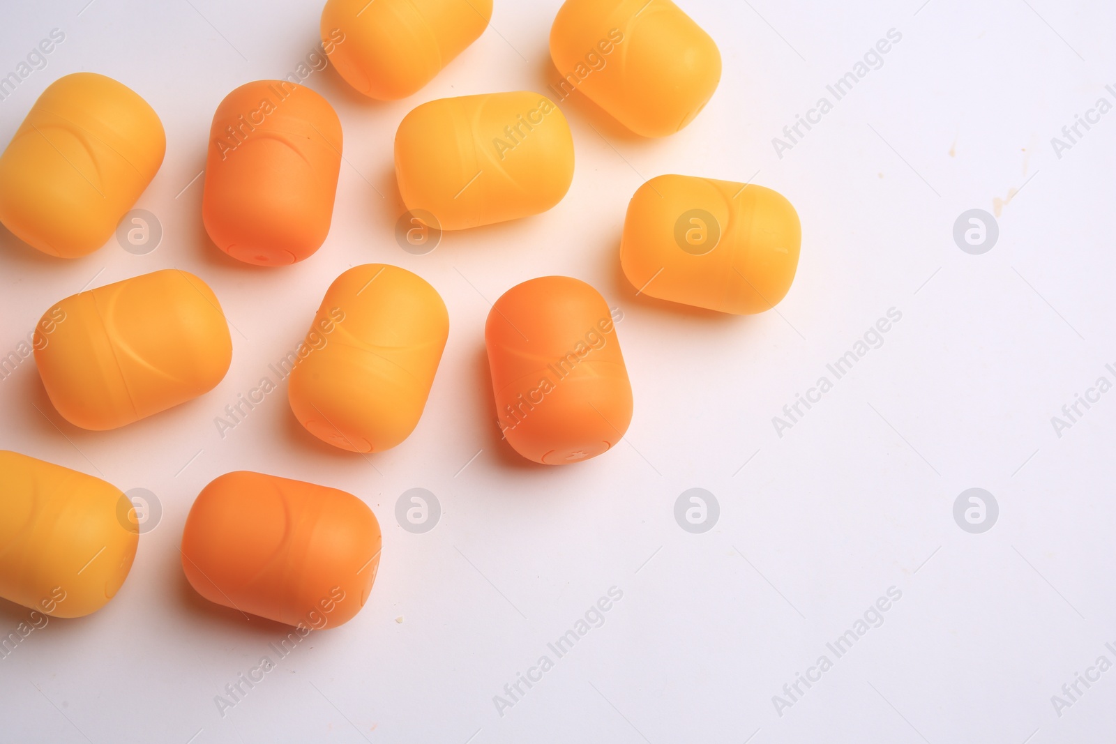 Photo of Sveti Vlas, Bulgaria - June 30, , 2023: Orange plastic capsules from Kinder Surprise Eggs on white background, above view and space for text