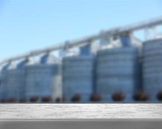 Image of Empty stone surface and blurred view of modern grain elevator. Space for text