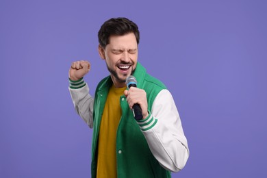 Photo of Handsome man with microphone singing on purple background