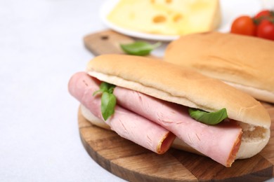 Photo of Delicious sandwich with ham and basil on white table, closeup