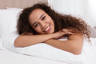 Photo of Happy African American woman lying on bed at home