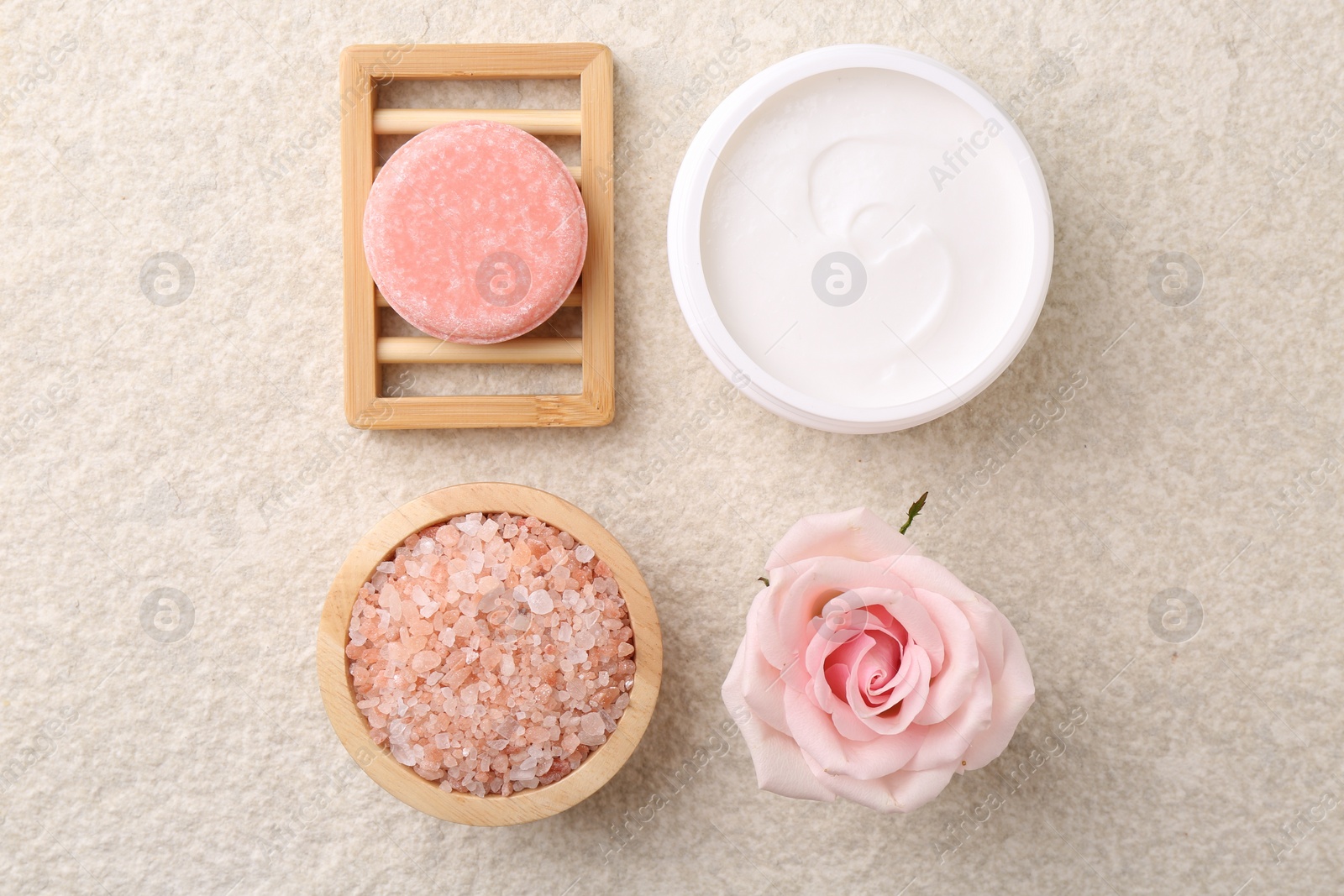 Photo of Flat lay composition with moisturizing cream in open jar and other body care products on light textured table