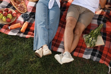 Couple having picnic on plaid outdoors, closeup