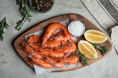 Delicious cooked shrimps served with rosemary and lemon on grey table, flat lay