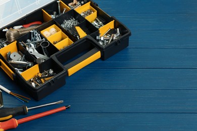 Photo of Plastic box with different furniture fittings and tools on blue wooden table, space for text