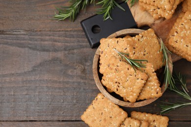 Photo of Cereal crackers with flax, sesame seeds and rosemary on wooden table, flat lay. Space for text