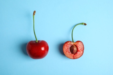 Photo of Cut and whole sweet cherries on light blue background, top view