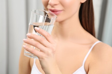 Photo of Healthy habit. Closeup of woman drinking fresh water from glass indoors