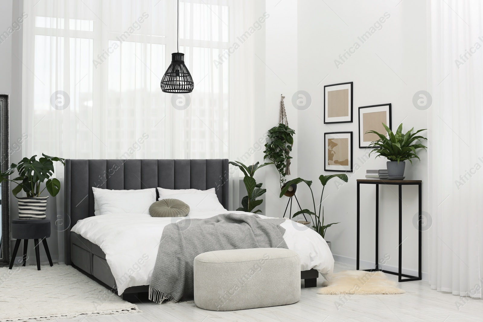 Photo of Large comfortable bed and beautiful houseplants in room. Bedroom interior