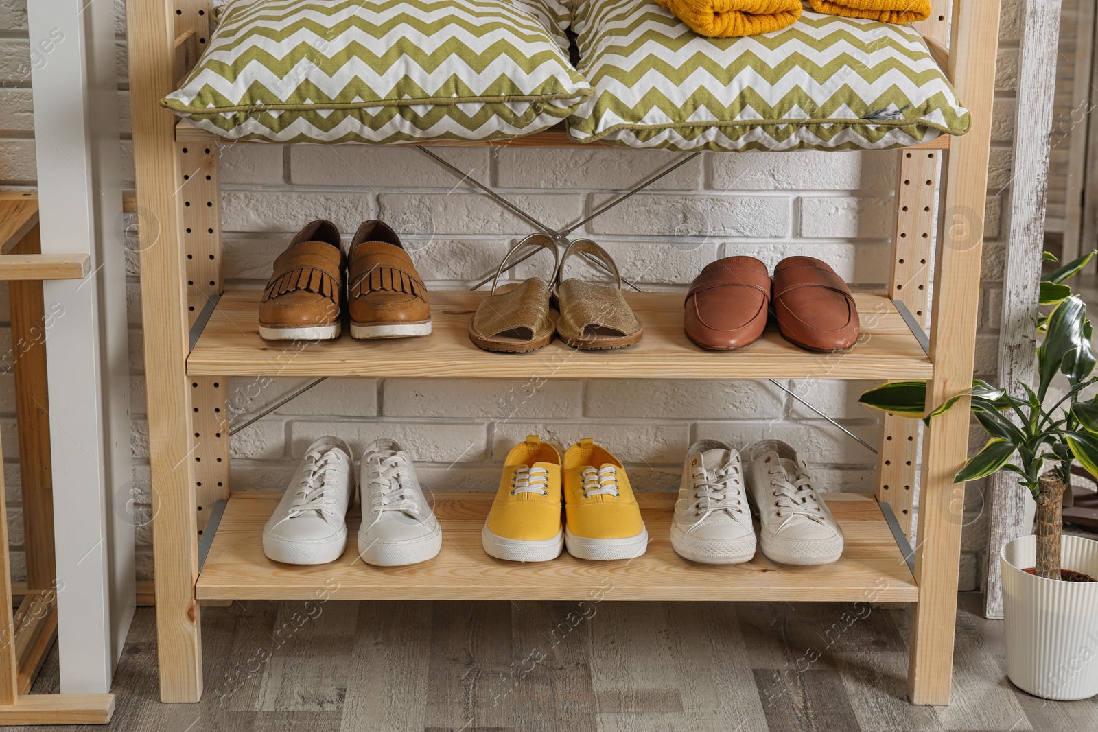 Photo of Stylish hallway interior with shoe rack near brick wall