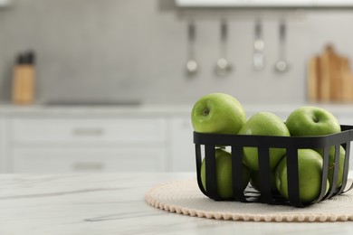 Fresh green apples on white table in kitchen, space for text