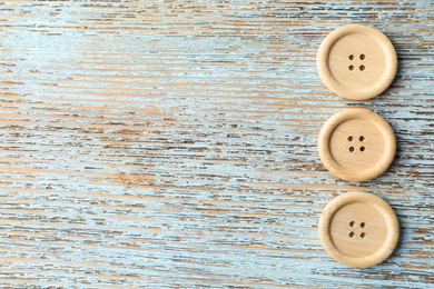 Photo of Sewing buttons on light wooden background, flat lay. Space for text