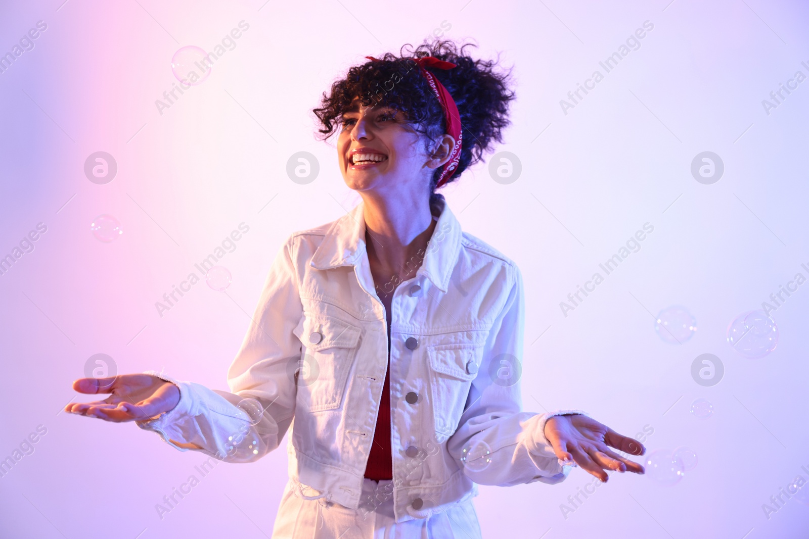 Photo of Beautiful young woman and bubbles on color background in neon lights