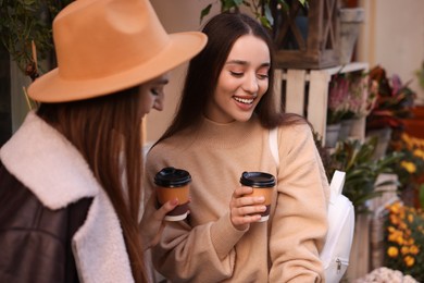 Photo of Happy friends with paper cups of coffee outdoors