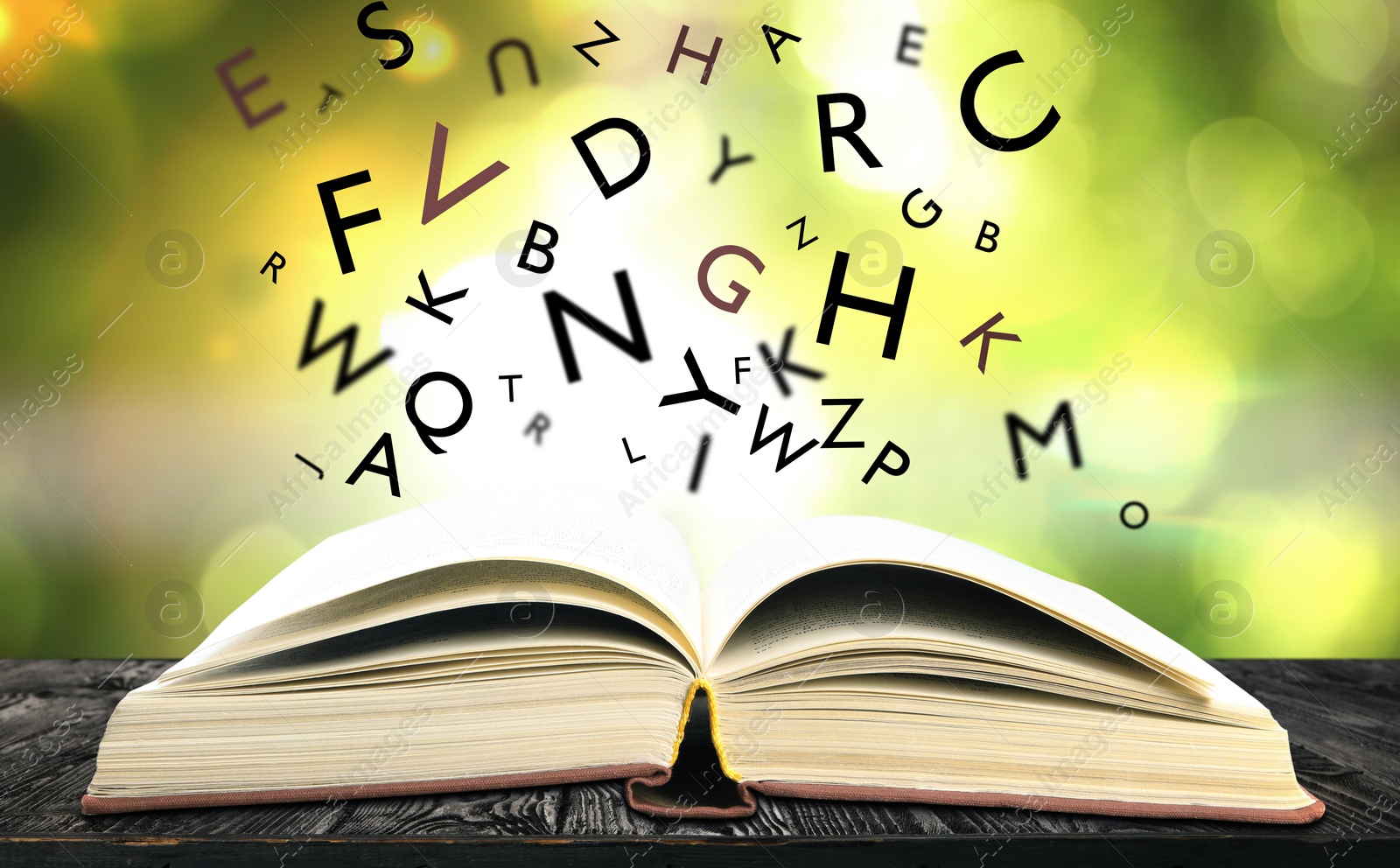 Image of Open book with letters flying out of it on wooden table against blurred background