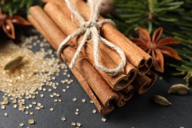 Photo of Cinnamon sticks and other spices on gray table, closeup