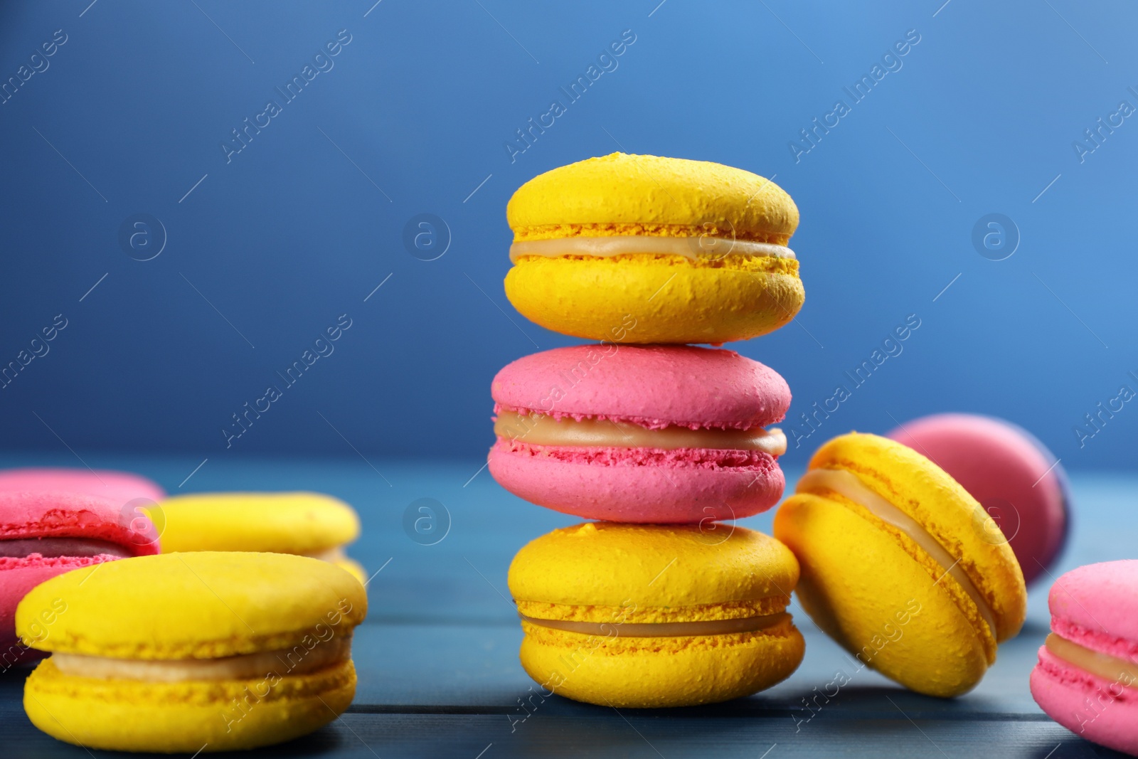 Photo of Delicious colorful macarons on blue wooden table