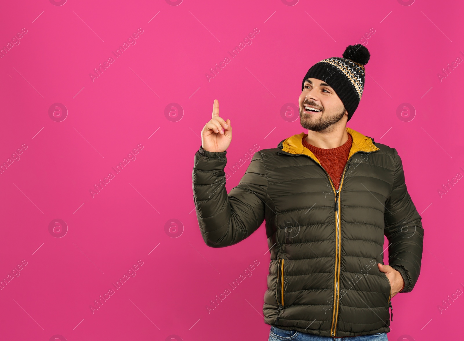 Photo of Happy young man in warm clothes on pink background, space for text. Winter vacation