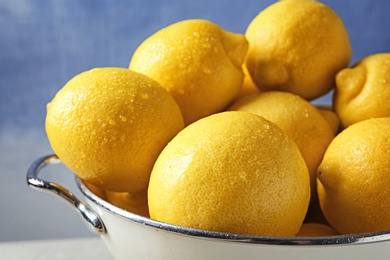 Photo of Colander with ripe lemons against color background