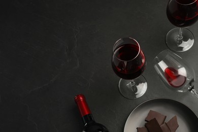 Photo of Composition with tasty red wine and chocolate on black table, above view. Space for text
