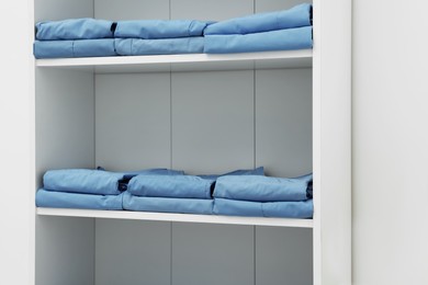 Photo of Light blue medical uniforms on white rack