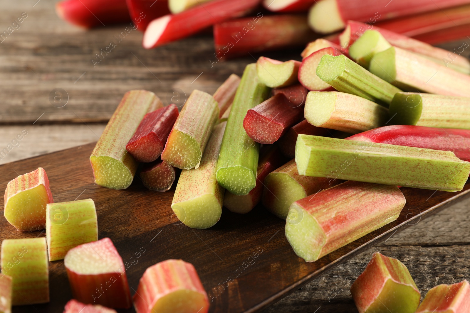 Photo of Many cut rhubarb stalks on wooden table, closeup