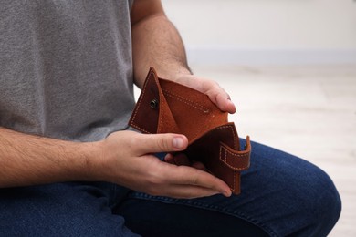 Photo of Man with empty wallet at home, closeup