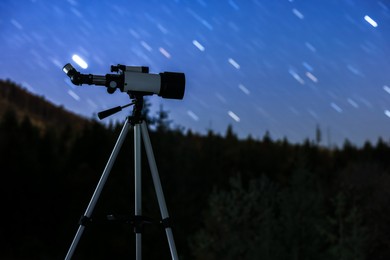 Modern telescope under night sky with star trails outdoors. Learning astronomy