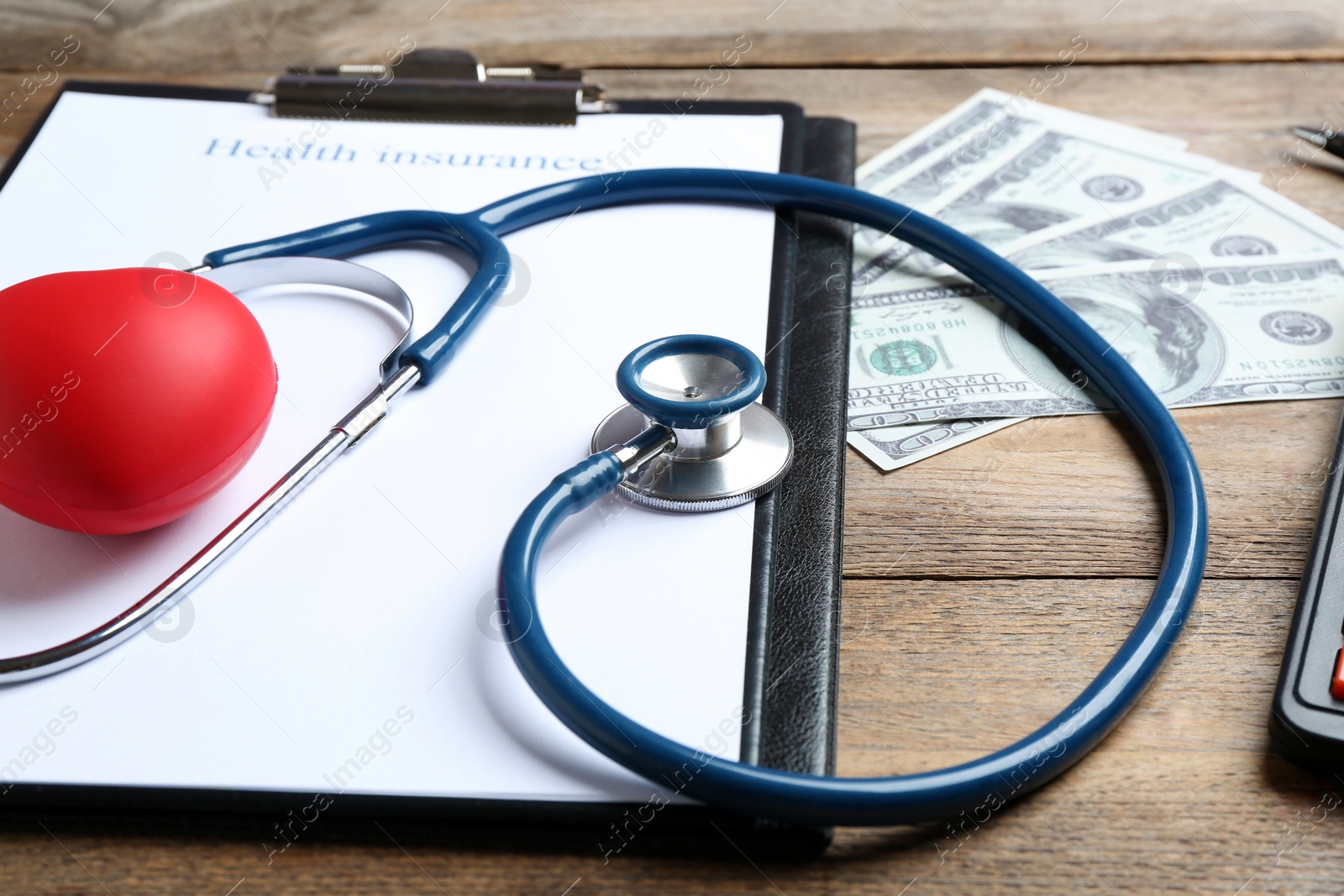 Photo of Health insurance form, red heart with stethoscope and money on wooden surface