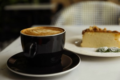 Cup of fresh coffee and dessert on table indoors, closeup