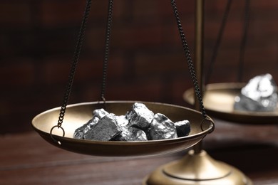 Photo of Vintage scales with silver nuggets on wooden table, closeup