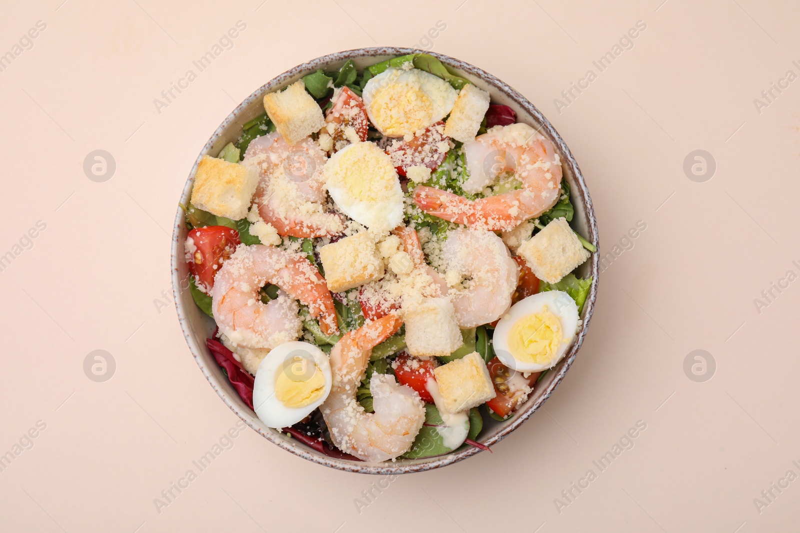 Photo of Delicious Caesar salad with shrimps on beige background, top view