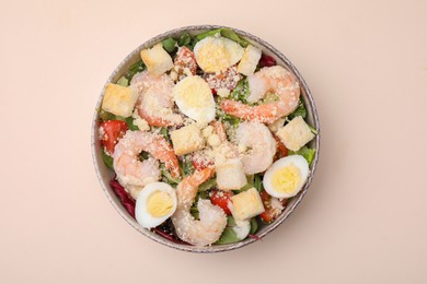 Delicious Caesar salad with shrimps on beige background, top view