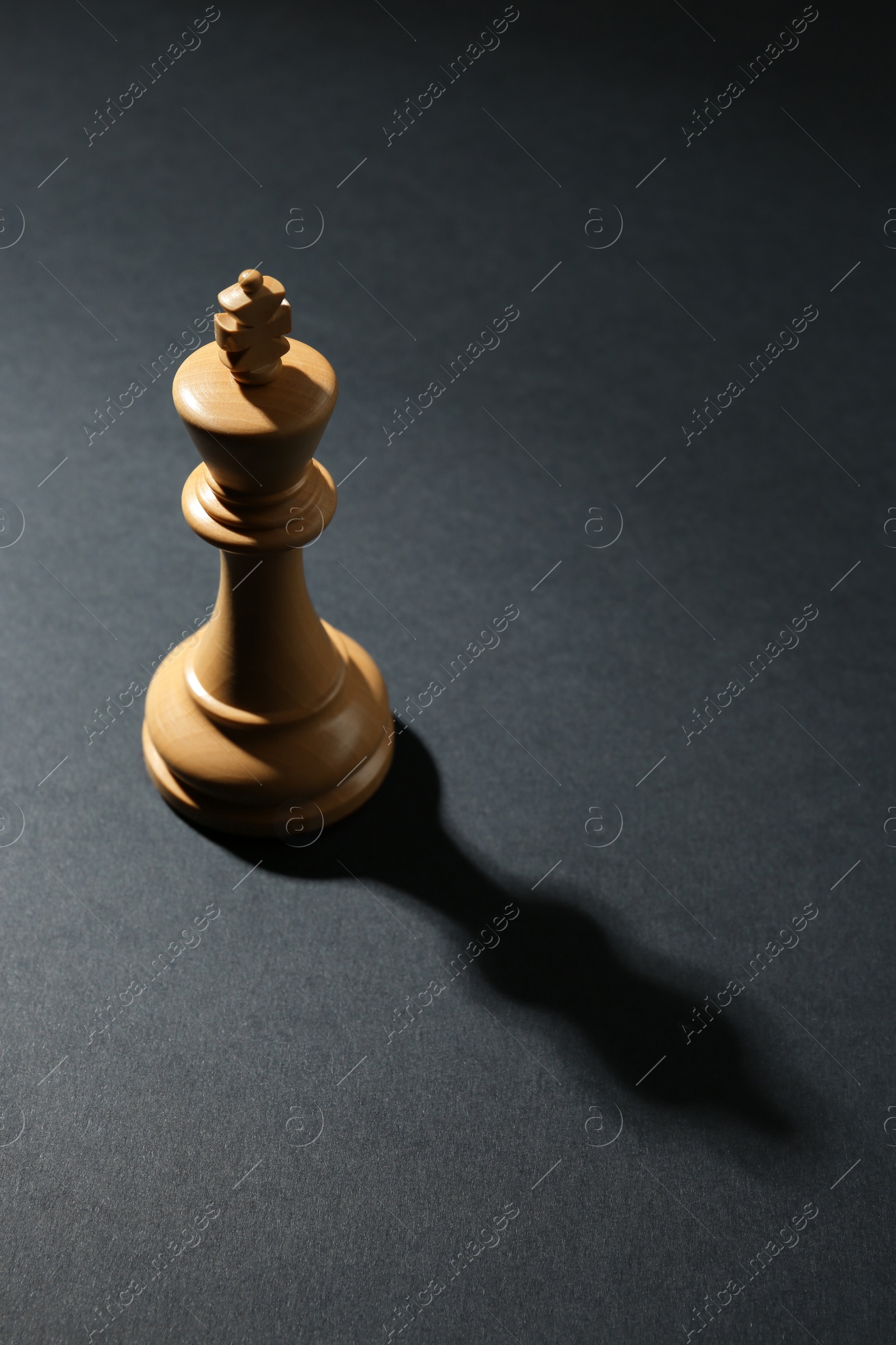 Photo of White wooden chess king on dark background, above view