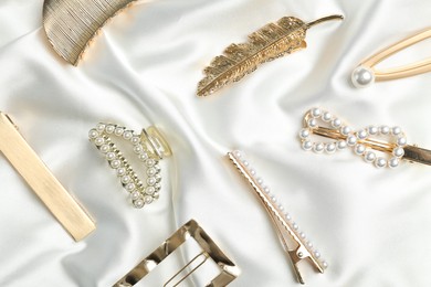Photo of Beautiful different hair clips on white fabric, flat lay