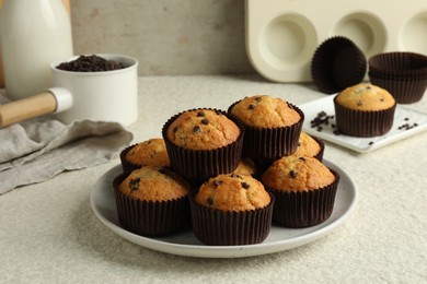 Photo of Delicious sweet muffins with chocolate chips on light textured table