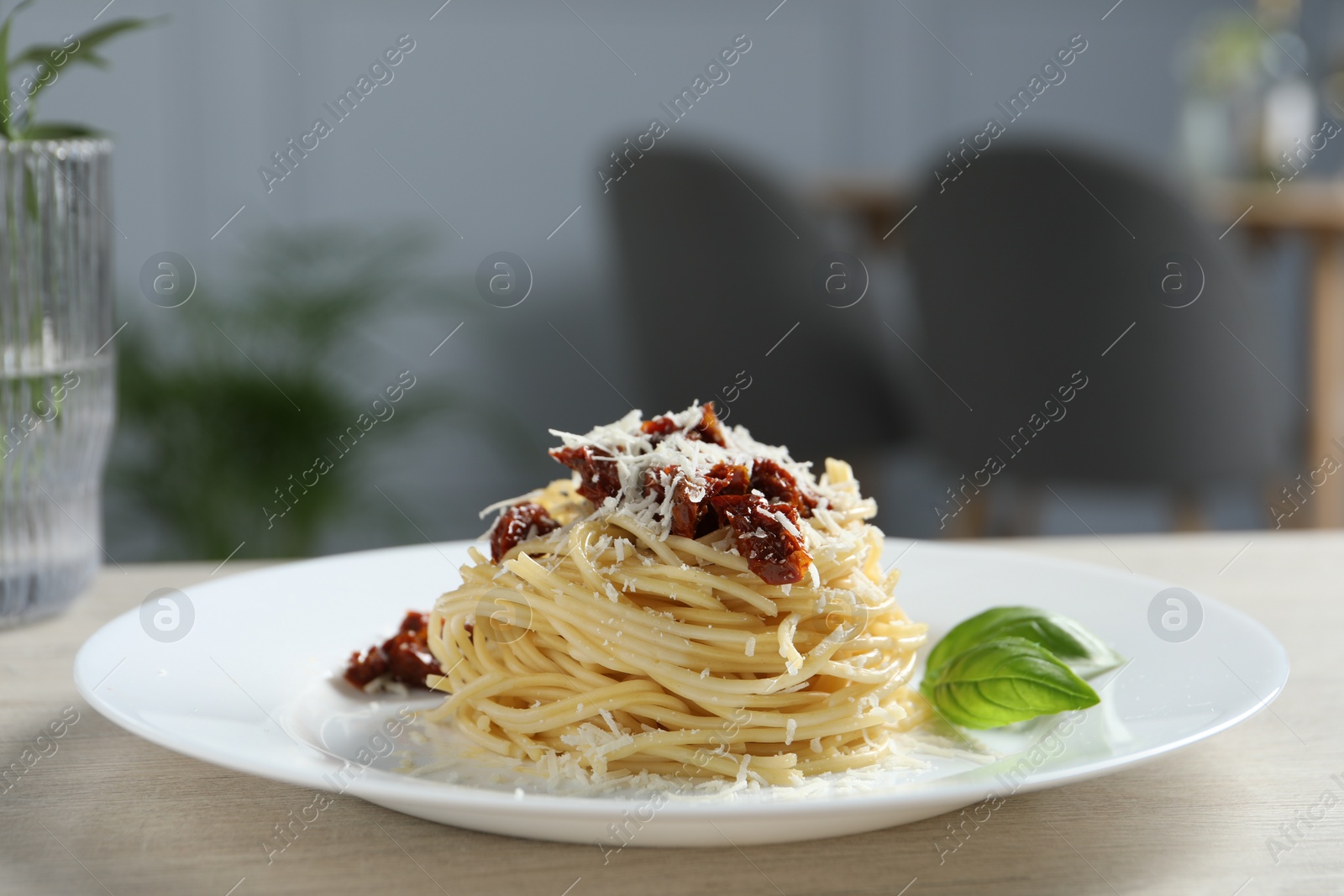 Photo of Tasty spaghetti with sun-dried tomatoes and parmesan cheese on wooden table in restaurant, closeup. Exquisite presentation of pasta dish