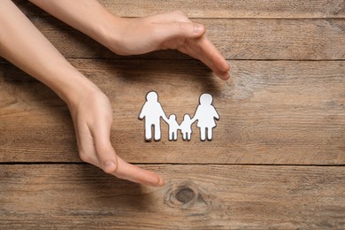 Woman with paper family cutout at wooden table, top view