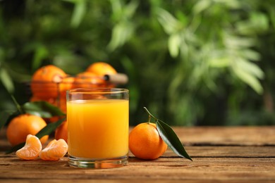 Photo of Glass of fresh tangerine juice and fruits on wooden table. Space for text