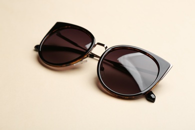 Photo of Stylish sunglasses on beige background. Fashionable accessory