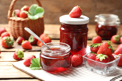 Photo of Delicious pickled strawberry jam and fresh berries on wooden table