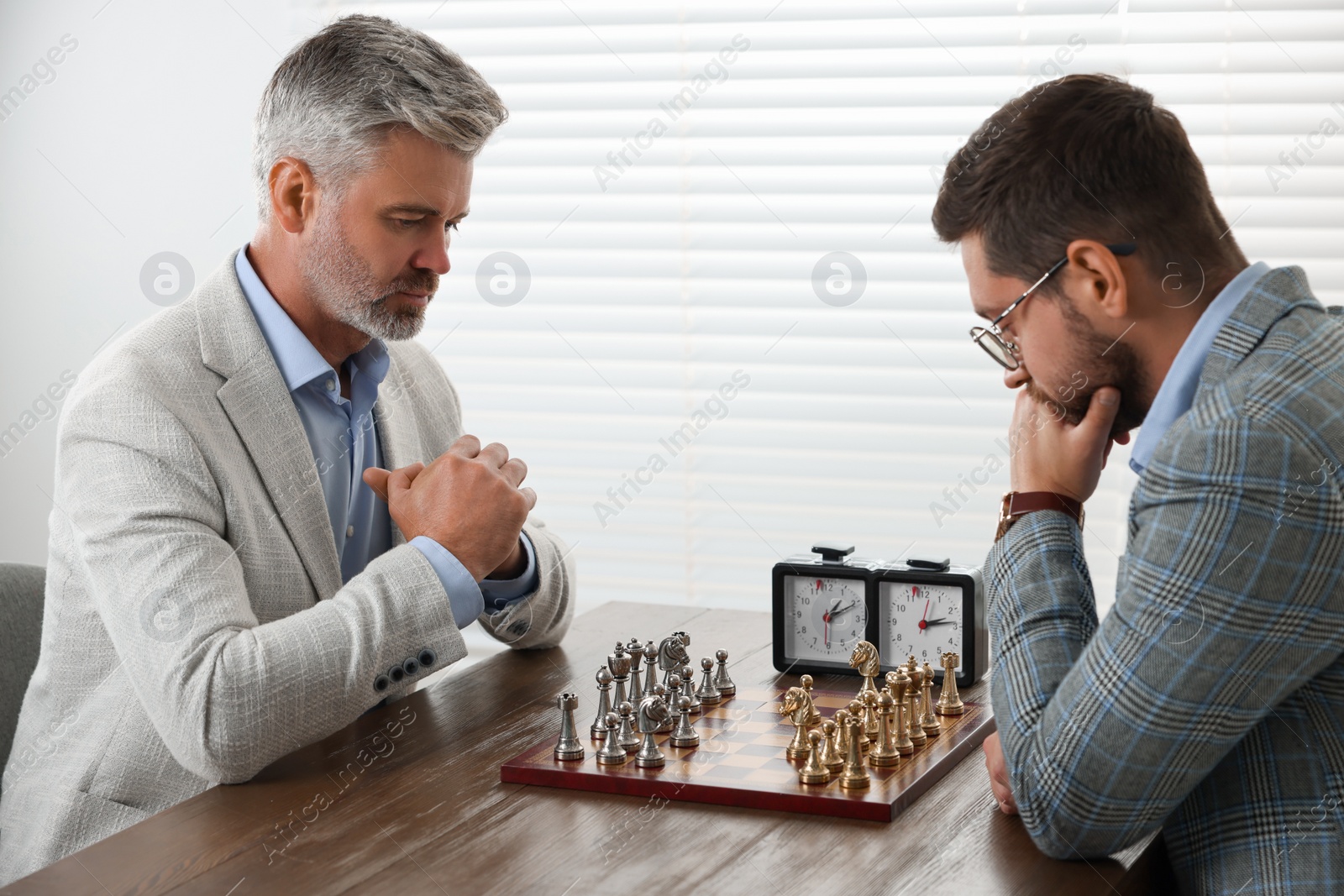 Photo of Men playing chess during tournament at table indoors