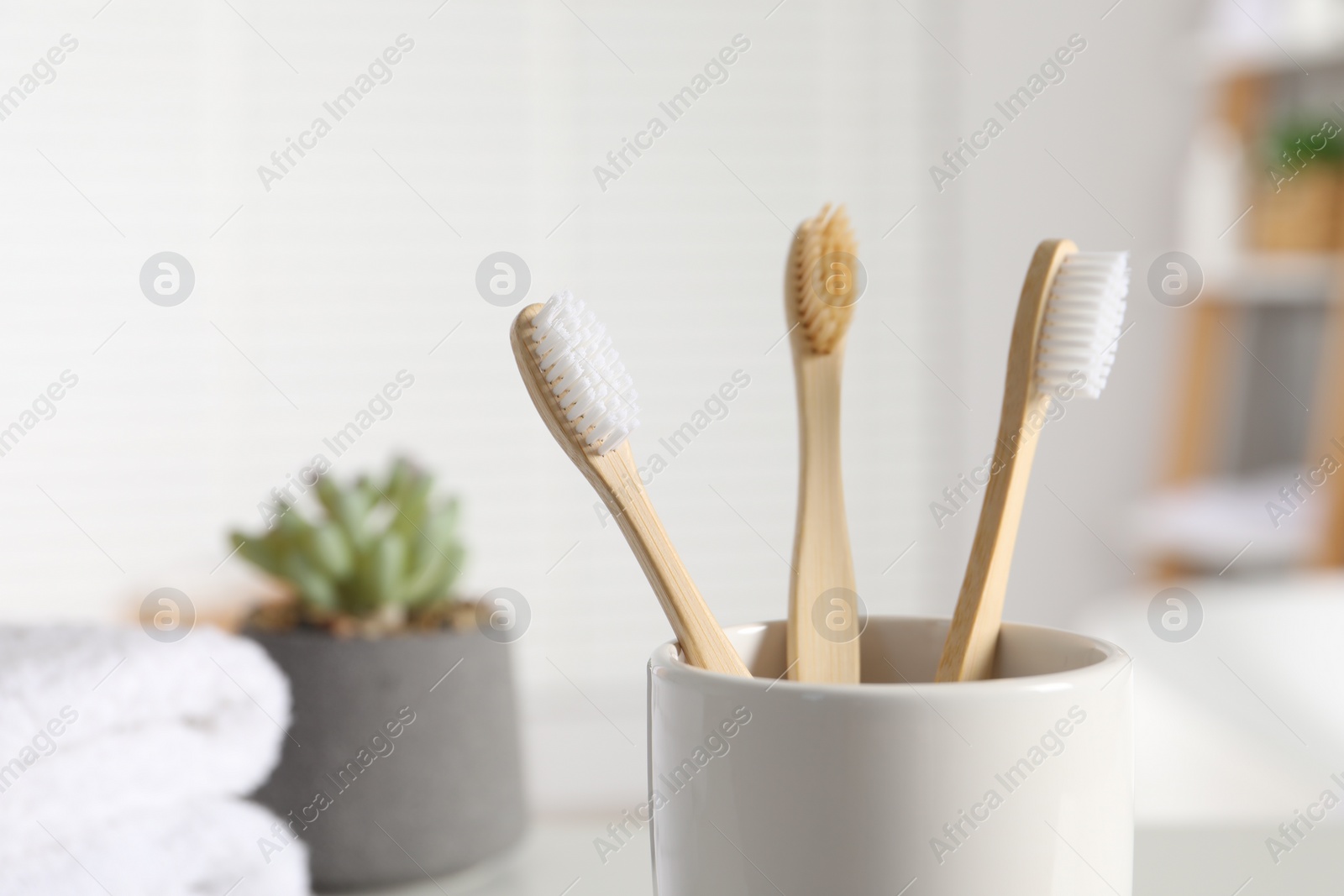 Photo of Bamboo toothbrushes in holder on blurred background, closeup. Space for text